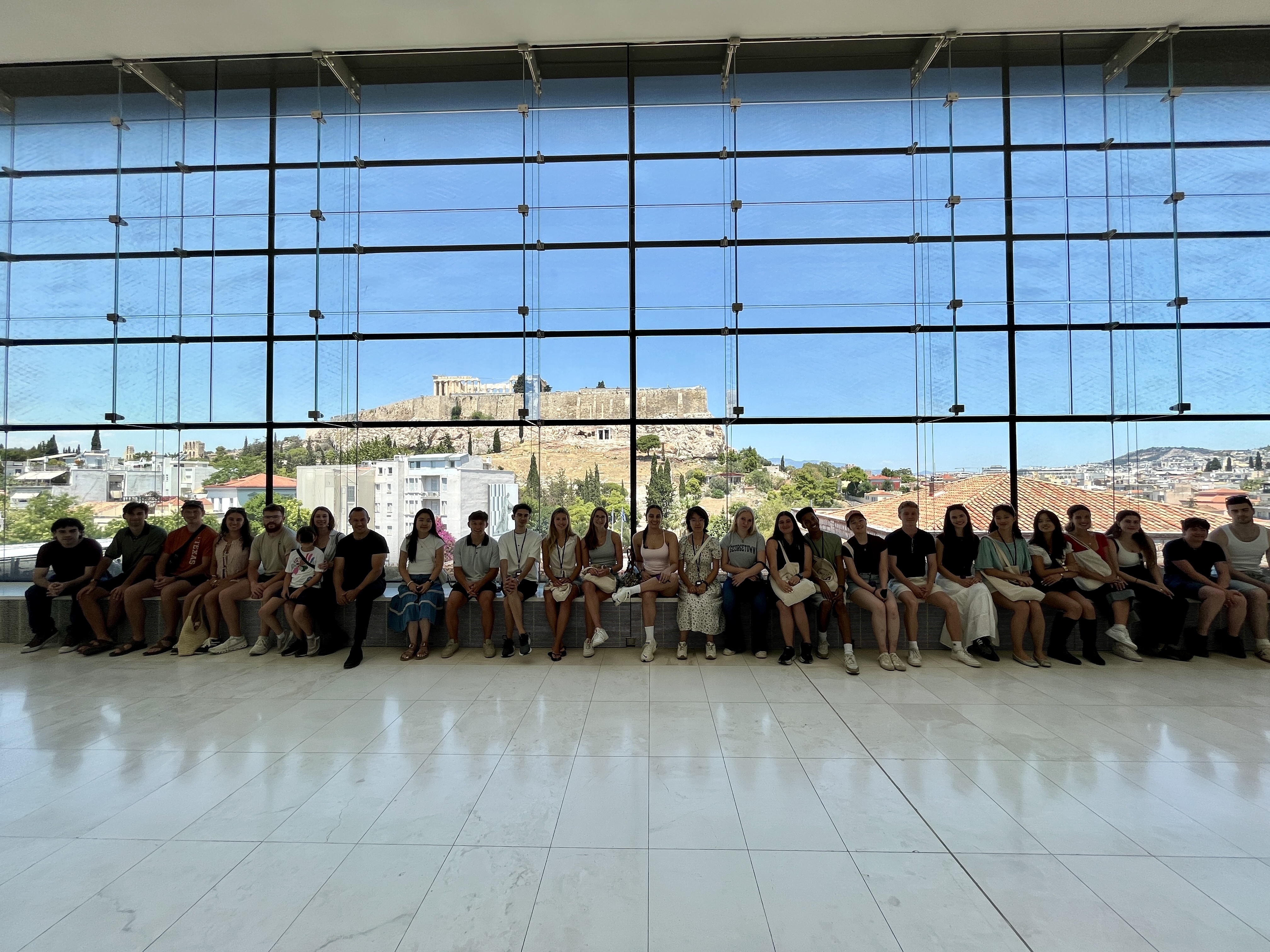 Συμμετέχοντες σε προγράμματα του ΚΕΣ στο Μουσείο Ακρόπολης, με θέα την Ακρόπολη στο βάθος.