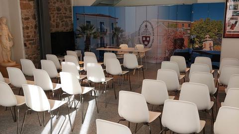 Αίθουσα με καρέκλες που είναι σε πέντε σειρές και κοιτάζουν προς ένα πανό