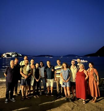 Η ομάδα του εργαστηρίου στην παραλία το σούρουπο, με το φωτισμένο Μπούρτζι και τον κόλπο του Ναυπλίου στο βάθος.