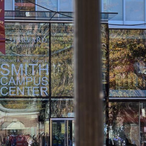 Γυάλινη πρόσοψη του Smith Campus Center με αντανακλάσεις δέντρων και την επιγραφή «Harvard University».