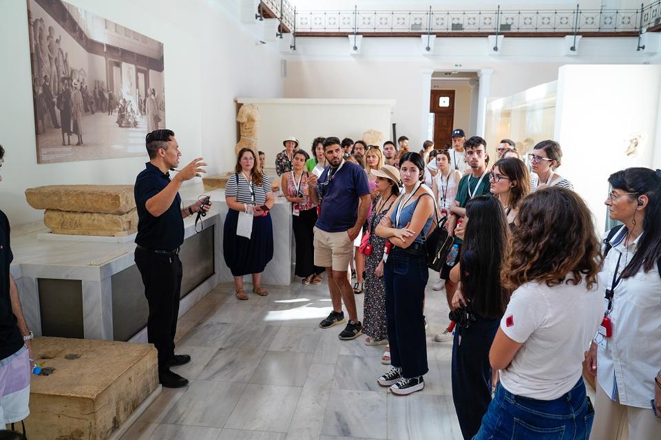 Ομάδα ανθρώπων διάφορων ηλικιών σε μουσειακό χώρο ακούει με προσοχή τον καθηγητή Stocking να μιλά και να χειρονομεί με τα χέρια του.
